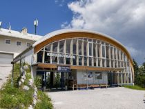 Die Kreuzeckbahn ist die älteste Bahn in Garmisch-Partenkirchen. Nein - natürlich nicht diese Version hier, denn die stammt aus dem Jahr 2002. Den Vorgänger allerdings gab es mit ein paar Umbauten seit dem Jahr 1926, in dem die Kreuzeckbahn als erste Seilschwebebahn in Bayern ihren Betrieb aufnahm. Die Kapazität von anfangs sogar nur 150 Personen in der Stunde reichte natürlich nie und so wurde nach zahlreichen Umbauten und den begrenzt möglichen Erweiterungen der Kapazität im Winter 2002 die heutige Anlage mit einer Förderleistung von 2.000 Personen pro Stunde in Betrieb genommen.

Die Bahn ist auch im Sommer extrem beliebt und führt auf etwa 1.600 Meter Seehöhe. Von dort geht es unter anderem auf einem Fahrweg weiter zur Hochalm, wo sich die nächste Seilbahn anschließt. • © alpintreff.de